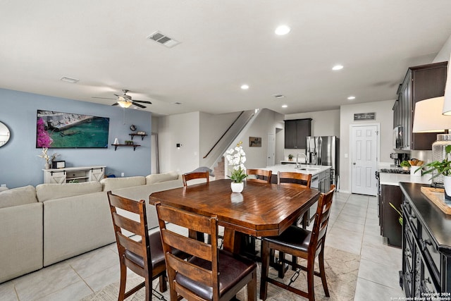 tiled dining area with ceiling fan and sink