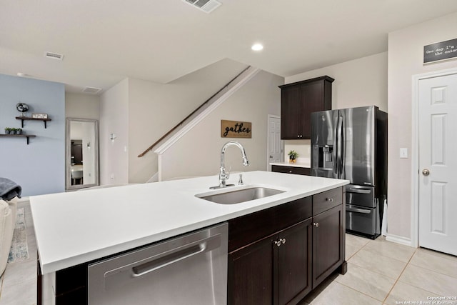 kitchen featuring appliances with stainless steel finishes, dark brown cabinets, a kitchen island with sink, sink, and light tile patterned floors