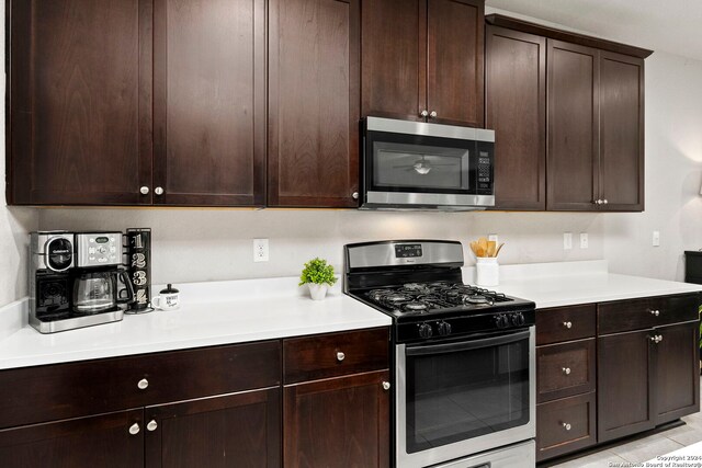 kitchen with light tile patterned flooring, dark brown cabinetry, and stainless steel appliances