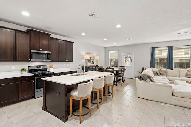 kitchen with a center island with sink, sink, light tile patterned floors, and stainless steel appliances