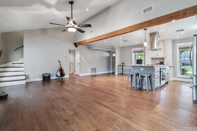 unfurnished living room featuring beamed ceiling, hardwood / wood-style floors, high vaulted ceiling, and ceiling fan