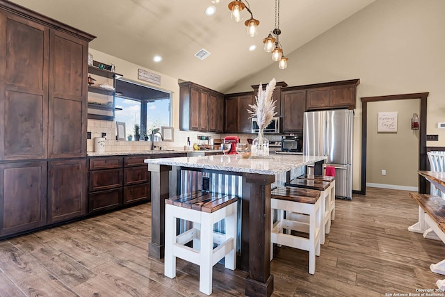 kitchen featuring light hardwood / wood-style floors, decorative backsplash, light stone countertops, and appliances with stainless steel finishes