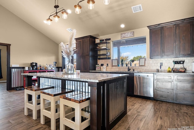 kitchen featuring stainless steel dishwasher, vaulted ceiling, hardwood / wood-style floors, a center island, and hanging light fixtures