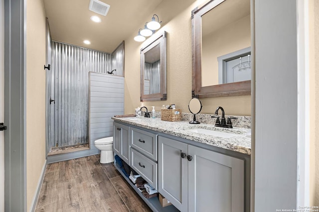 bathroom with hardwood / wood-style flooring, vanity, toilet, and a shower