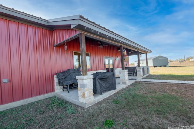 view of side of home featuring a lawn, ceiling fan, a patio, and a storage shed