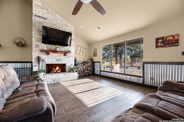 living room featuring ceiling fan, a stone fireplace, wood-type flooring, and high vaulted ceiling