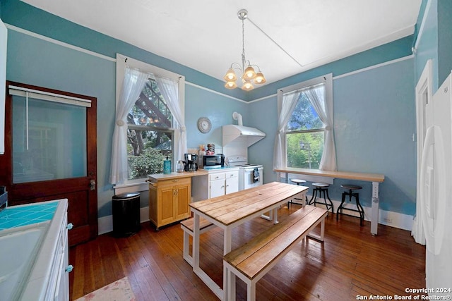 dining space featuring a healthy amount of sunlight, wood-type flooring, and a notable chandelier