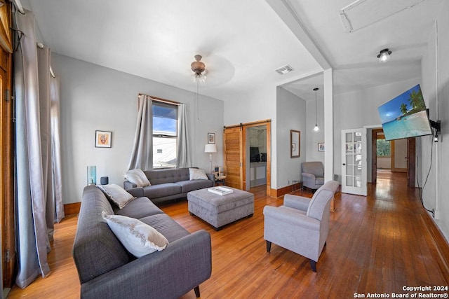 living room featuring a barn door, ceiling fan, and light hardwood / wood-style flooring