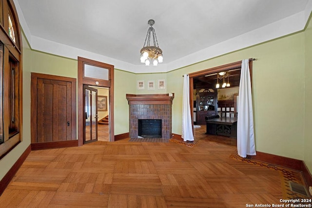 unfurnished living room featuring a tile fireplace, light parquet floors, and a notable chandelier