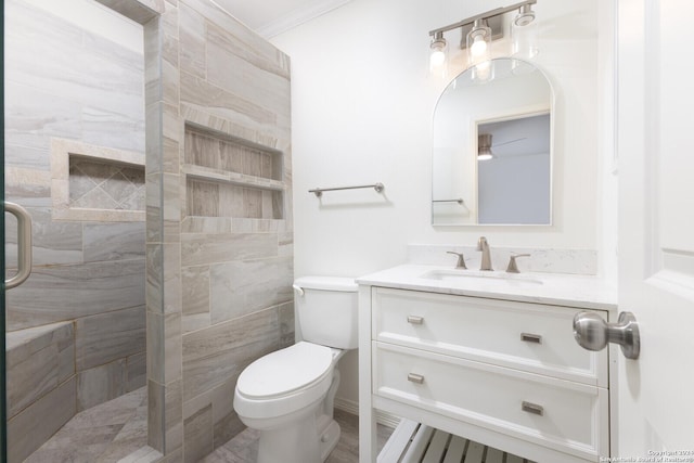 bathroom with tiled shower, vanity, toilet, and ornamental molding