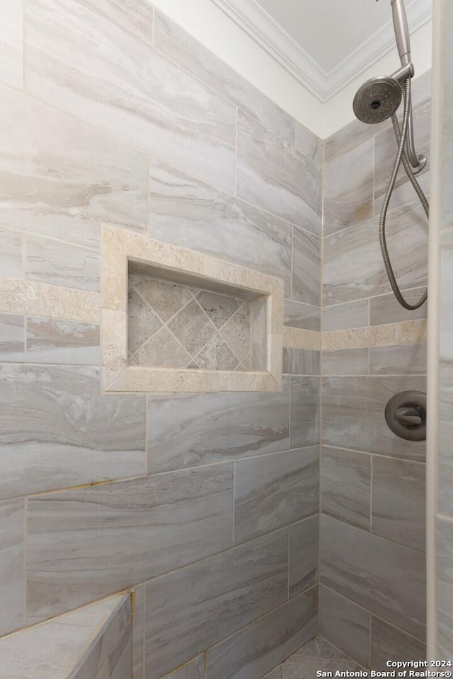 bathroom with a tile shower and crown molding