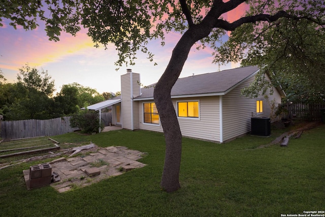 property exterior at dusk featuring a yard, central AC, and a patio area