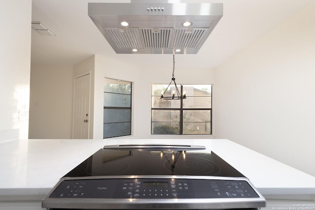 kitchen featuring island range hood, range, a wealth of natural light, and an inviting chandelier