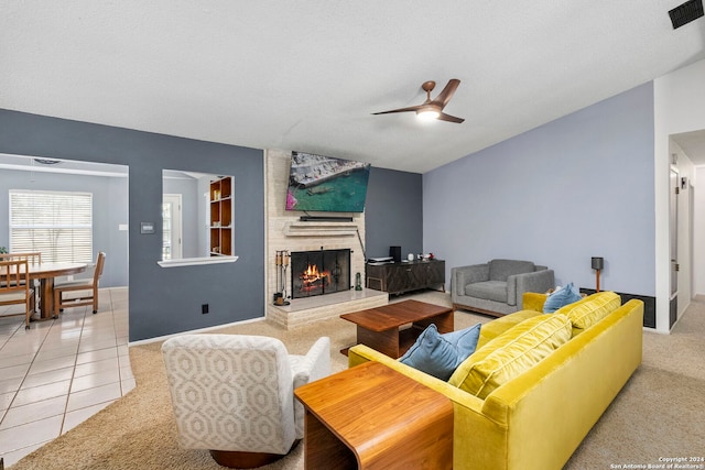 tiled living room with a textured ceiling, a brick fireplace, and ceiling fan