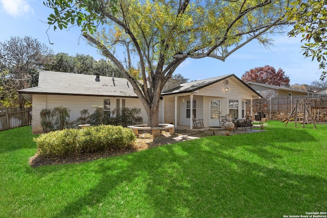 rear view of property featuring a playground, a patio area, and a yard