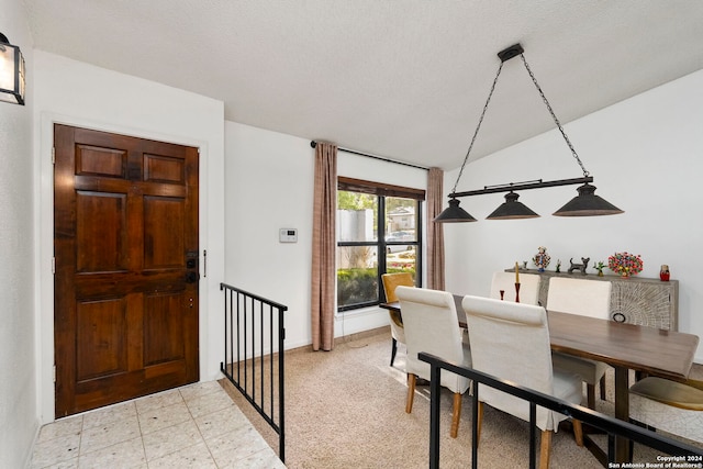 dining space featuring a textured ceiling and vaulted ceiling