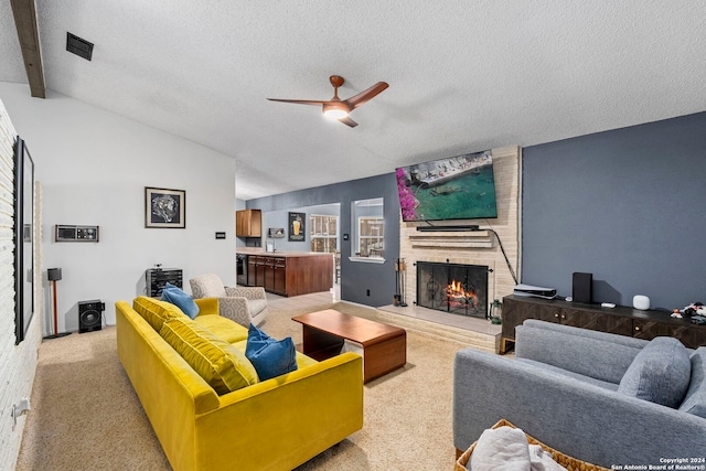 carpeted living room with a textured ceiling, vaulted ceiling with beams, a brick fireplace, and ceiling fan