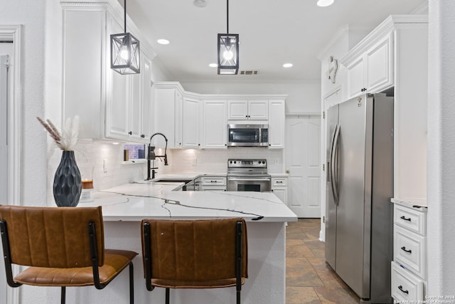 kitchen featuring kitchen peninsula, a kitchen bar, stainless steel appliances, decorative light fixtures, and white cabinets