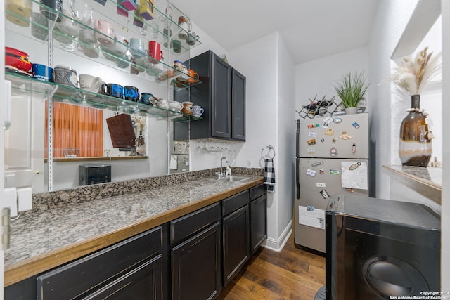 kitchen featuring light stone counters, sink, dark wood-type flooring, and stainless steel refrigerator