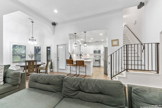 living room with sink, beamed ceiling, light hardwood / wood-style floors, and an inviting chandelier