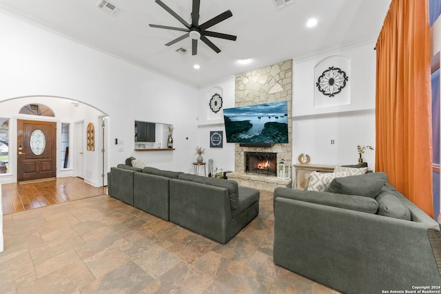 living room with hardwood / wood-style floors, a stone fireplace, ceiling fan, and ornamental molding