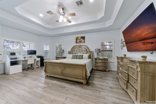 bedroom featuring a tray ceiling, ceiling fan, crown molding, and light hardwood / wood-style flooring