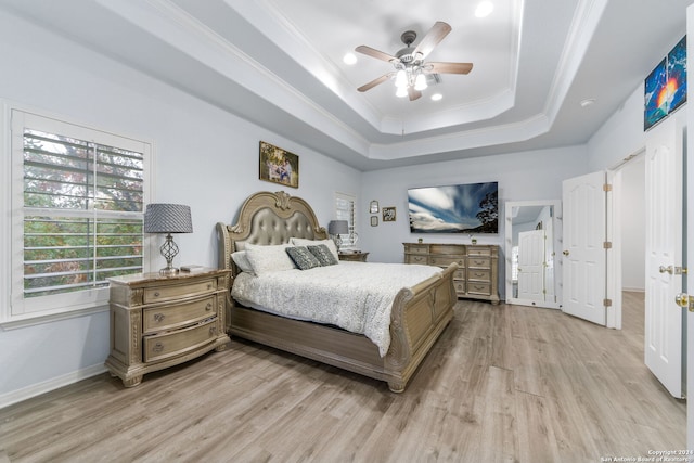 bedroom with light hardwood / wood-style floors, a raised ceiling, ceiling fan, and ornamental molding