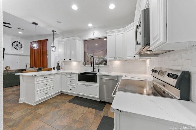 kitchen with kitchen peninsula, appliances with stainless steel finishes, decorative light fixtures, and white cabinetry