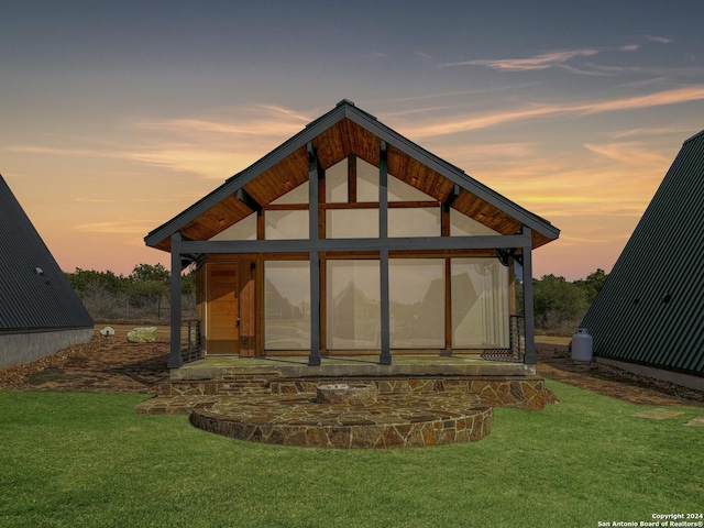 back house at dusk featuring a lawn