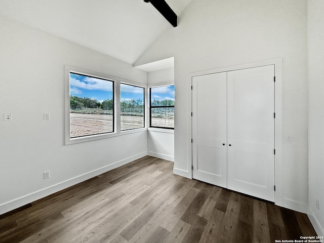 unfurnished bedroom featuring wood-type flooring, a closet, and lofted ceiling