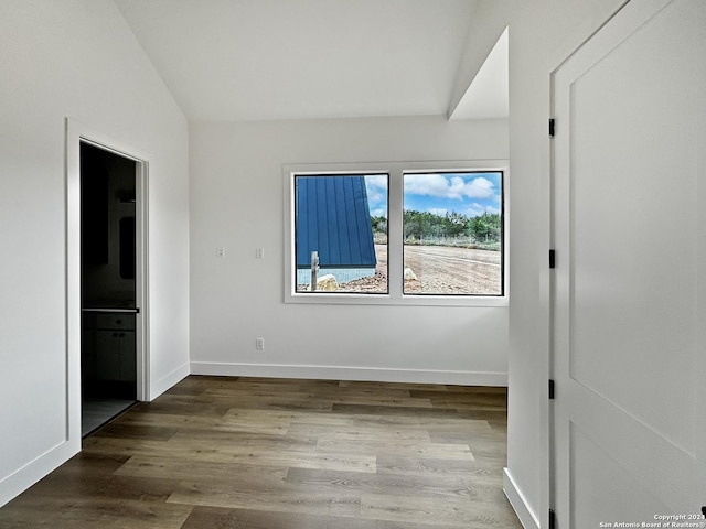 unfurnished bedroom with ensuite bathroom, lofted ceiling, and hardwood / wood-style flooring