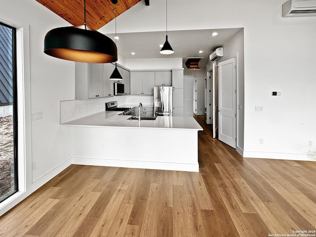 kitchen featuring an AC wall unit, kitchen peninsula, vaulted ceiling, gray cabinets, and appliances with stainless steel finishes