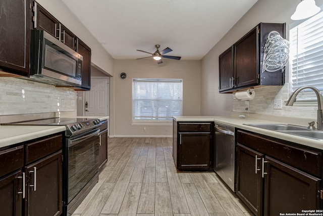 kitchen with backsplash, sink, appliances with stainless steel finishes, dark brown cabinets, and light hardwood / wood-style floors