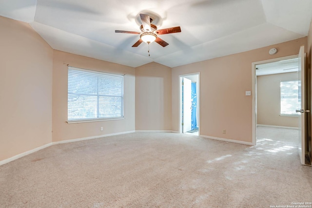 carpeted spare room with ceiling fan, a healthy amount of sunlight, and vaulted ceiling