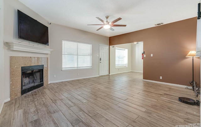 unfurnished living room featuring ceiling fan, a fireplace, and light wood-type flooring