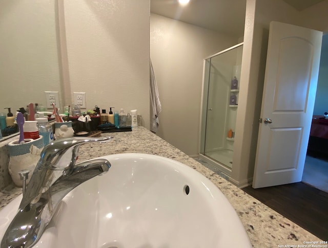 bathroom with wood-type flooring, vanity, and an enclosed shower