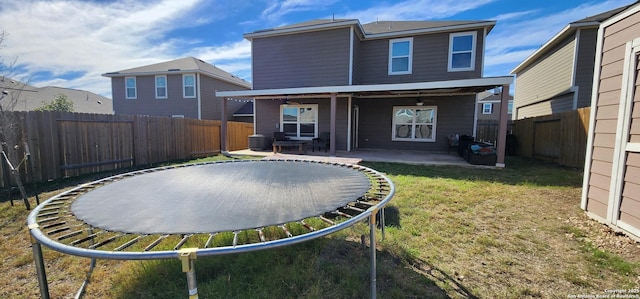 back of property featuring a patio area, a trampoline, and a yard