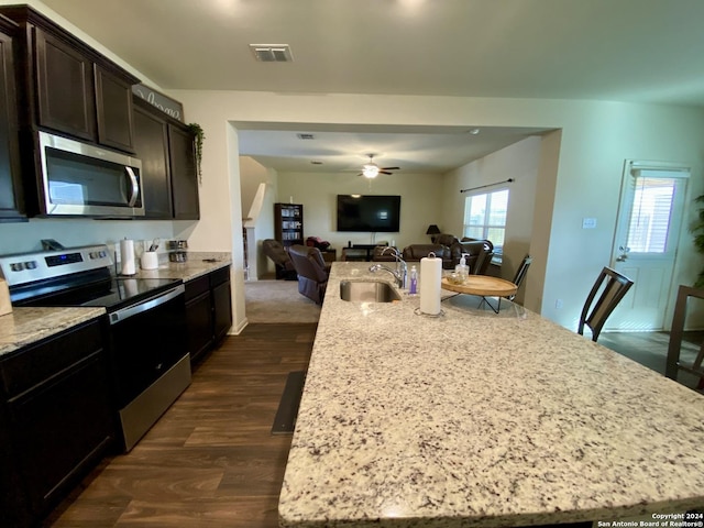 kitchen with ceiling fan, sink, an island with sink, and stainless steel appliances