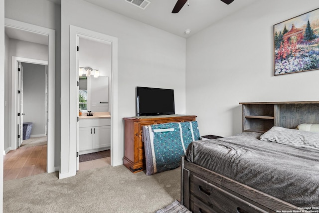 carpeted bedroom with connected bathroom, ceiling fan, and sink