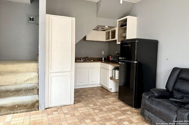 kitchen with sink, white cabinets, and black fridge