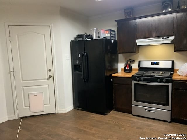 kitchen featuring hardwood / wood-style floors, wood counters, stainless steel gas range oven, black fridge, and dark brown cabinetry