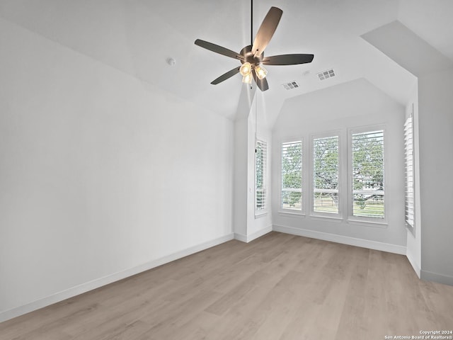 empty room featuring ceiling fan, vaulted ceiling, and light wood-type flooring