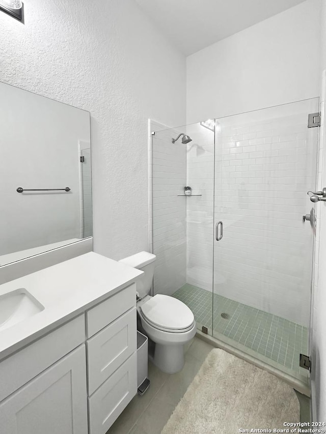 bathroom with toilet, vanity, tile patterned floors, and an enclosed shower