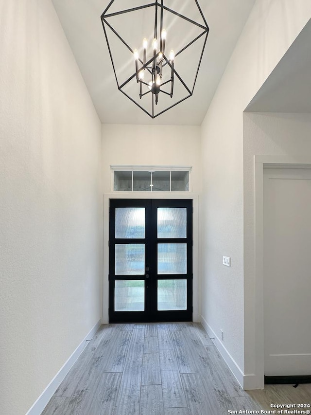 foyer entrance featuring french doors, hardwood / wood-style flooring, and a notable chandelier