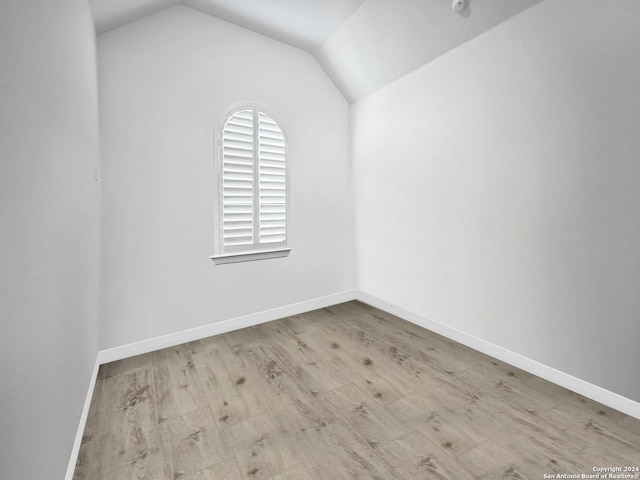 spare room featuring light hardwood / wood-style floors and lofted ceiling