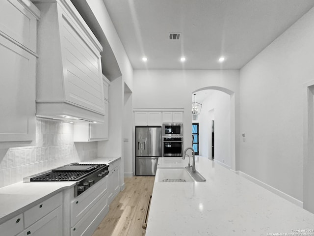 kitchen featuring appliances with stainless steel finishes, tasteful backsplash, sink, white cabinets, and light hardwood / wood-style floors