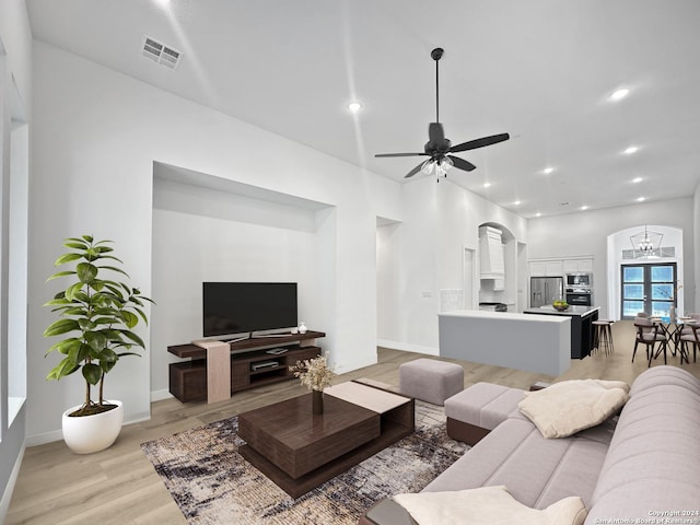 living room featuring ceiling fan with notable chandelier and light hardwood / wood-style floors