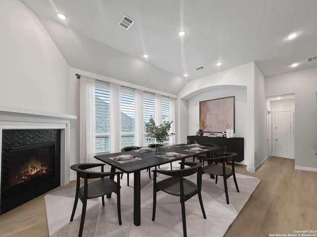 dining room featuring a tiled fireplace and light hardwood / wood-style flooring