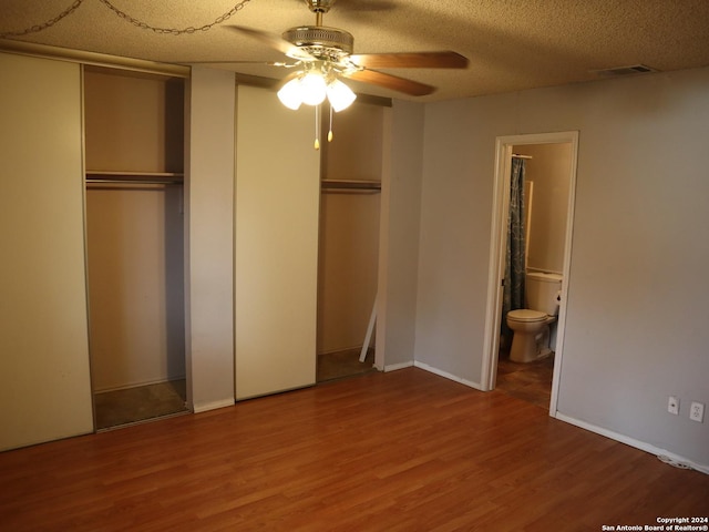 unfurnished bedroom with wood-type flooring, a textured ceiling, ensuite bathroom, and ceiling fan