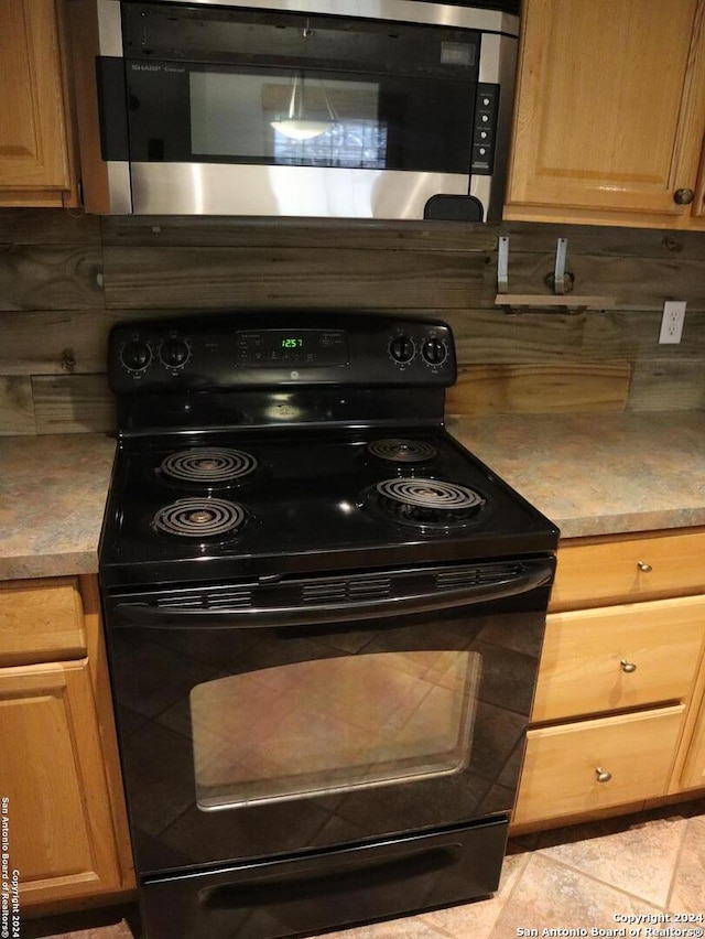 kitchen featuring decorative backsplash, light tile patterned floors, and black electric range oven